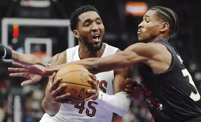 Cleveland Cavaliers' Donovan Mitchell (45) is fouled by Toronto Raptors' Ochai Agbaji (30) during the first half of an NBA basketball game in Toronto on Wednesday, Feb. 12, 2025. (Frank Gunn/The Canadian Press via AP)