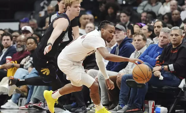 Cleveland Cavaliers' Darius Garland, right, battles for the ball with Toronto Raptors' Gradey Dick during the first half of an NBA basketball game in Toronto on Wednesday, Feb. 12, 2025. (Frank Gunn/The Canadian Press via AP)