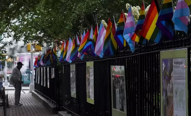 FILE - A visitor views a historical exhibit of the Gay rights movement, displayed on fencing dressed with flags affirming LGBTQ identity at the Stonewall National Monument, Wednesday, June 22, 2022, in New York. (AP Photo/Bebeto Matthews, File)