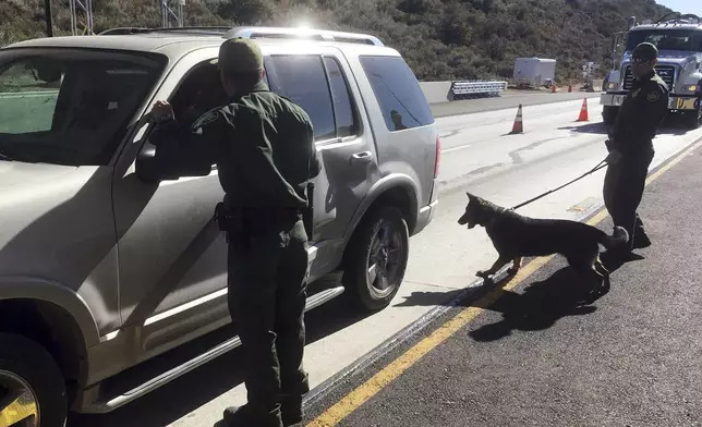 FILE - Border patrol agents use a drug sniffing dog to check vehicles at California's Pine Valley checkpoint, on the main route from Arizona to San Diego, Dec. 14, 2017 (AP Photo/Elliot Spagat, File)