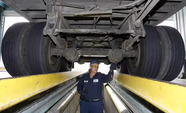 FILE - California Highway Patrol commercial vehicle inspector Ruben Montanez inspects the undercarriage of a truck entering the U.S. from Mexico at the CHP's Otay Mesa Inspection Station Thursday, Sept. 6, 2007, in San Diego. (AP Photo/Denis Poroy)