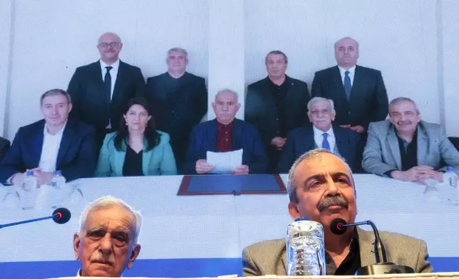 Pro-Kurdish Peoples' Equality and Democracy Party, or DEM, delegation members release an statement from the jailed leader of the rebel Kurdistan Workers' Party, or PKK, Abdullah Ocalan, center at the background photo, in Istanbul, Turkey, Thursday, Feb. 27, 2025. (AP Photo/Khalil Hamra)