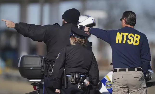A member of the NTSB talks to Philadelphia Police officers near the scene where a small plane crashed in Philadelphia, Saturday, Feb. 1, 2025. (AP Photo/Matt Rourke)