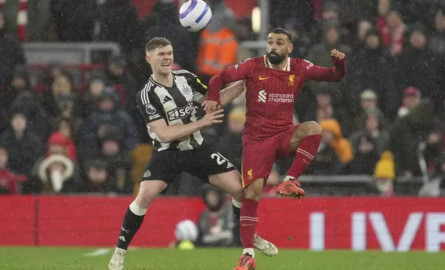 Newcastle's Lewis Hall, left, challenges Liverpool's Mohamed Salah during the English Premier League soccer match between Liverpool and Newcastle United at Anfield in Liverpool, Wednesday, Feb. 26, 2025. (AP Photo/Jon Super)