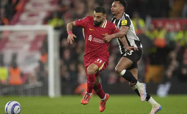 Newcastle's Jacob Murphy, right, challenges Liverpool's Mohamed Salah during the English Premier League soccer match between Liverpool and Newcastle United at Anfield in Liverpool, Wednesday, Feb. 26, 2025. (AP Photo/Jon Super)