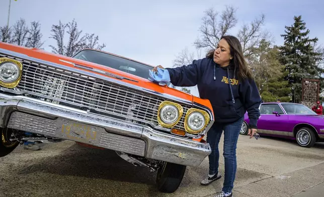 Vicki Garcia cleans her 1963 lowrider Chevy Impala outside of the State Capitol in Santa Fe, N.M., on Lowrider Day, Tuesday, Feb. 11, 2025. (AP Photo/Roberto E. Rosales)