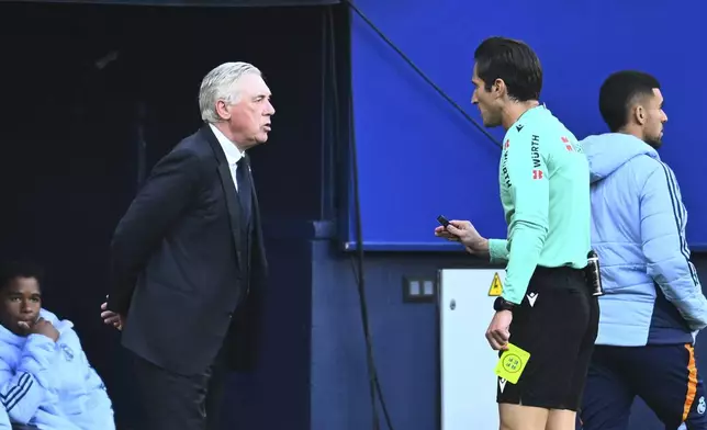 Real Madrid's head coach Carlo Ancelotti speaks with the referee after receiving a yellow card during a Spanish La Liga soccer match between Osasuna and Real Madrid at El Sardar stadium in Pamplona, Spain, Saturday, Feb. 15, 2025. (AP Photo/Miguel Oses)