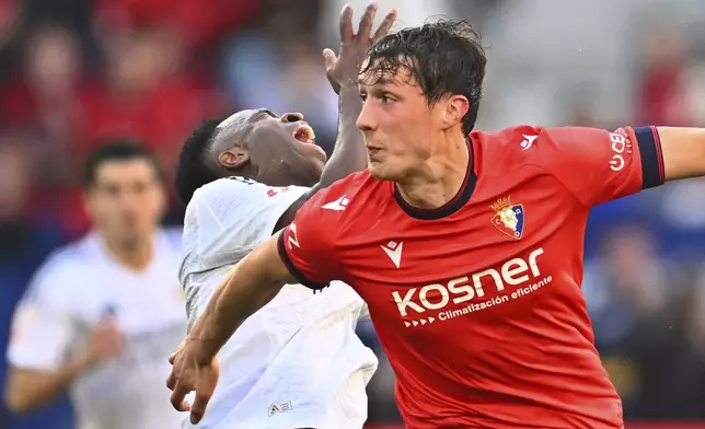Real Madrid's Vinicius Junior, rear centre, clashes with Osasuna's Jorge Herrando during a Spanish La Liga soccer match between Osasuna and Real Madrid at El Sardar stadium in Pamplona, Spain, Saturday, Feb. 15, 2025. (AP Photo/Miguel Oses)