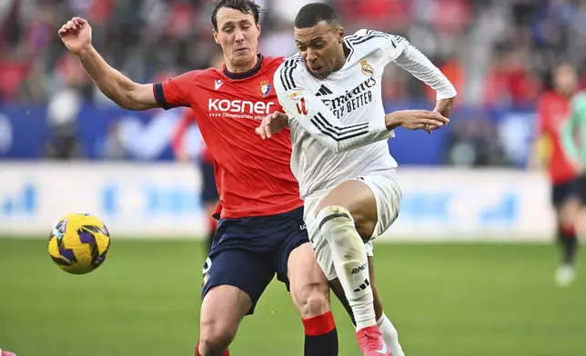 Real Madrid's Kylian Mbappe, right is challenged by Osasuna's Jorge Herrando during a Spanish La Liga soccer match between Osasuna and Real Madrid at El Sardar stadium in Pamplona, Spain, Saturday, Feb. 15, 2025. (AP Photo/Miguel Oses)