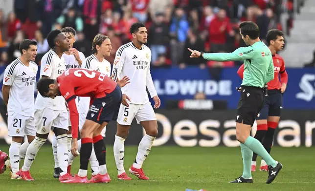 Real Madrid's Jude Bellingham, centre, protests to the referee after being shown a red card during a Spanish La Liga soccer match between Osasuna and Real Madrid at El Sardar stadium in Pamplona, Spain, Saturday, Feb. 15, 2025. (AP Photo/Miguel Oses)