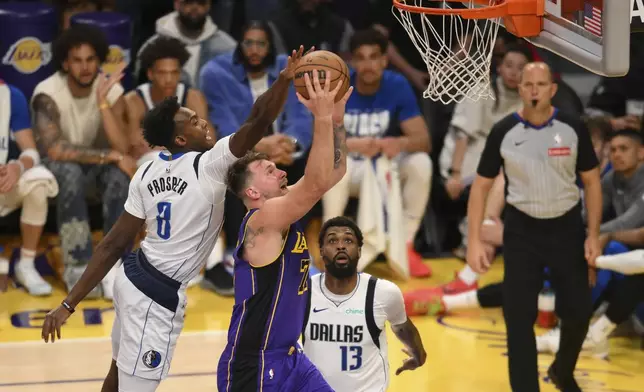 Dallas Mavericks forward Olivier-Maxence Prosper, left, blocks a shot by Los Angeles Lakers guard Luka Doncic during the second half of an NBA basketball game Tuesday, Feb. 25, 2025, in Los Angeles. (AP Photo/Kyusung Gong)