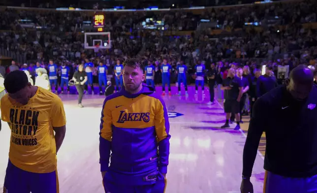 Los Angeles Lakers guard Luka Doncic, center, listens to the national anthem before an NBA basketball game against the Dallas Mavericks, Tuesday, Feb. 25, 2025, in Los Angeles. (AP Photo/Mark J. Terrill)