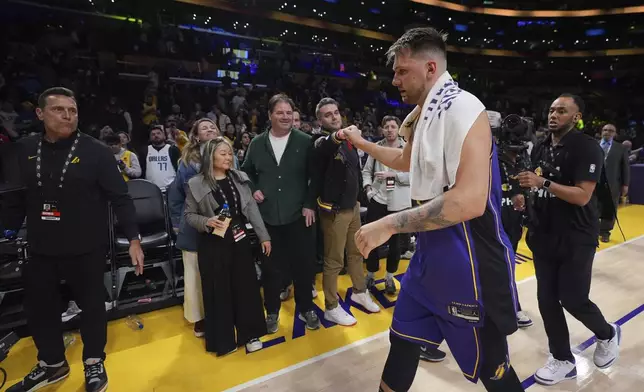 Los Angeles Lakers guard Luka Doncic, second from right, is greeted by a fan as he walks off the court after the team's victory over the Dallas Mavericks in an NBA basketball game Tuesday, Feb. 25, 2025, in Los Angeles. (AP Photo/Mark J. Terrill)