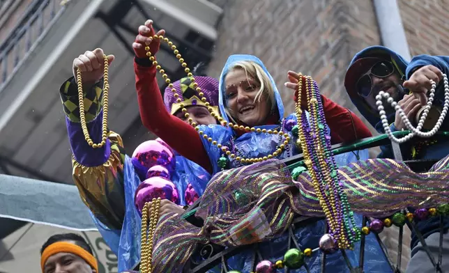 FILE - Revelers throw beads from balconies in the rain during Mardi Gras festivities in the French Quarter in New Orleans, March 4, 2014. AP Photo/Gerald Herbert, File)