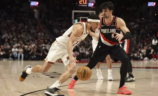 Phoenix Suns guard Devin Booker (1) drives to the basket as Portland Trail Blazers forward Deni Avdija (8) defends during the second half of an NBA basketball game Saturday, Feb. 1, 2025, in Portland, Ore. (AP Photo/Amanda Loman)