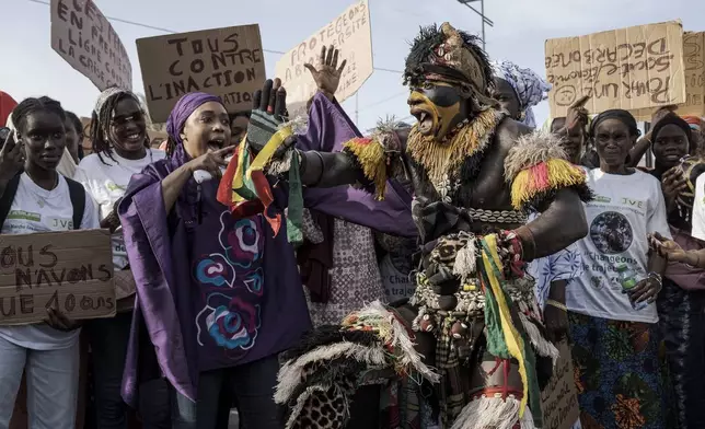 About 50 Senegalese women, joined by a performer dressed as a "faux lion", march through Dakar's Medina neighborhood in Senegal, during the fourth Women's March for Climate on Nov. 2, 2024. (AP Photo/Annika Hammerschlag)