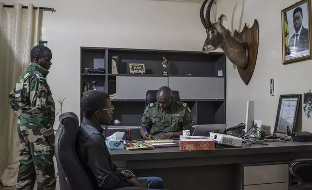 Paul Diedhiou, right, a colonel with Senegal's Direction of National Parks, works in his office at the DPN headquarters in Tambacounda, Senegal on Monday, Jan. 13, 2025. (AP Photo/Annika Hammerschlag)