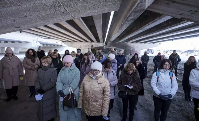 People gather under a destroyed bridge during a memorial ceremony to mark the third anniversary of the Russian invasion of Ukraine, in Irpyn, Ukraine, Feb. 24, 2025. (AP Photo/Evgeniy Maloletka)