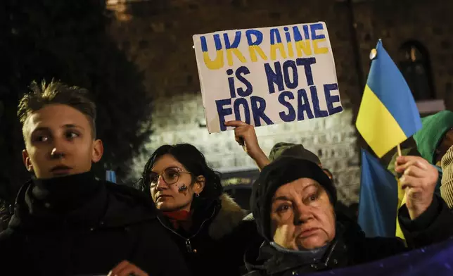 People hold Ukrainian flag and poster "Ukraine is not for sale" as Bulgarians and Ukrainian refugees express their solidarity with Ukrainians who have fought for their freedom for three years since the start of the Russian invasion, Sofia, Monday, Feb. 24, 2025. (AP Photo/Valentina Petrova)