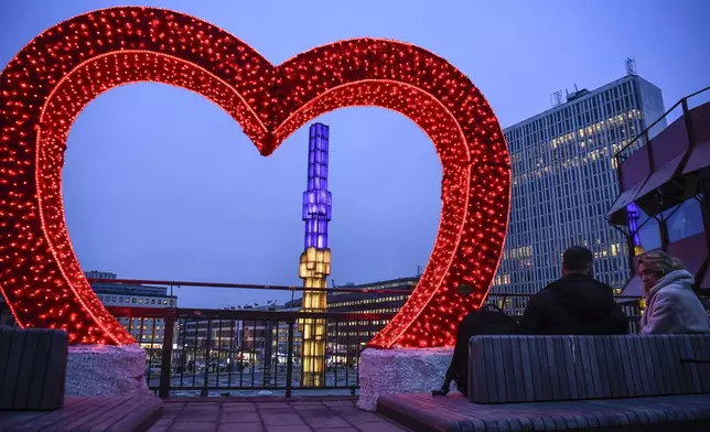 A red heart surrounds the glass obelisk lit up in the Ukrainian colours at Sergels torg in Stockholm, Sweden, Monday Feb. 24, 2025, marking the three year anniversary of the Russian invasion of Ukraine. (Oscar Olsson/TT via AP)