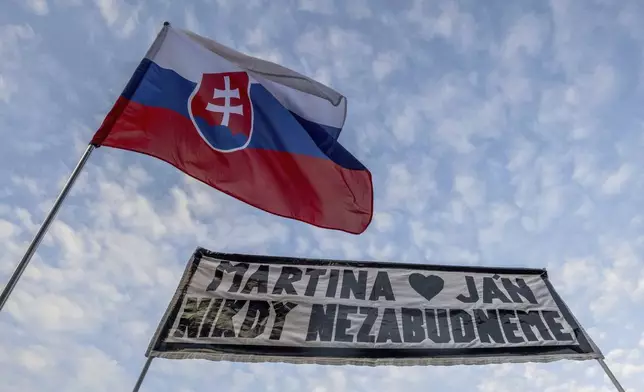 People gather in Bratislava, Slovakia on Friday Feb. 21, 2025, to mark the seventh anniversary of the slayings of an investigative journalist and his fiancee, Jan Kuciak and Martina Kusnirova. Banner reads: "Martina and Jan: We will never forget". (Vaclav Salek/CTK via AP)