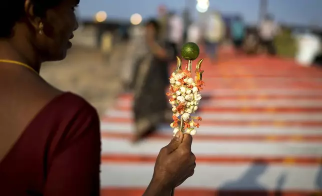 A devotee holds a trident, a symbol of Hindu god Shiva, as she climbs the steps of the Lingamanthula Swamy temple during a Hindu pilgrimage called the Peddagattu Jatara, in Suryapet, Telangana state, India, Sunday, Feb. 16, 2025. (AP Photo /Mahesh Kumar A.)