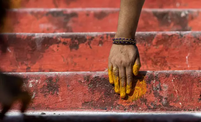 A devotee puts turmeric past on the steps of the Lingamanthula Swamy temple during a Hindu pilgrimage called the Peddagattu Jatara, in Suryapet, Telangana state, India, Sunday, Feb. 16, 2025. (AP Photo /Mahesh Kumar A.)