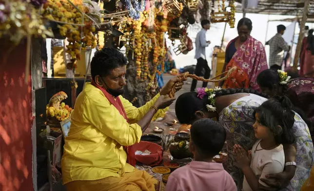 A priest blesses a devotee at the Lingamanthula Swamy temple during a Hindu pilgrimage called the Peddagattu Jatara, in Suryapet, Telangana state, India, Sunday, Feb. 16, 2025. (AP Photo /Mahesh Kumar A.)