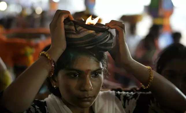 A devotee carries a lamp on her head at the Lingamanthula Swamy temple during during a Hindu pilgrimage called the Peddagattu Jatara, in Suryapet, Telangana state, India, Sunday, Feb. 16, 2025. (AP Photo /Mahesh Kumar A.)