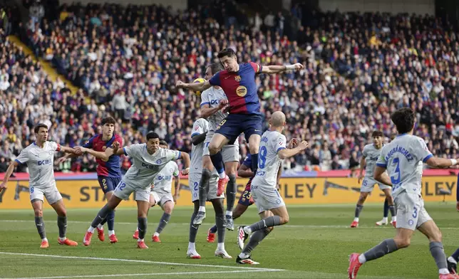 Barcelona's Robert Lewandowski, centre, jumps for the ball during a Spanish La Liga soccer match between Barcelona and Alaves at the Lluis Companys Olympic Stadium in Barcelona, Spain, Sunday Feb. 2, 2025. (AP Photo/Joan Monfort)