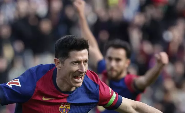 Barcelona's Robert Lewandowski, left, celebrates after scoring the opening goal during a Spanish La Liga soccer match between Barcelona and Alaves at the Lluis Companys Olympic Stadium in Barcelona, Spain, Sunday Feb. 2, 2025. (AP Photo/Joan Monfort)