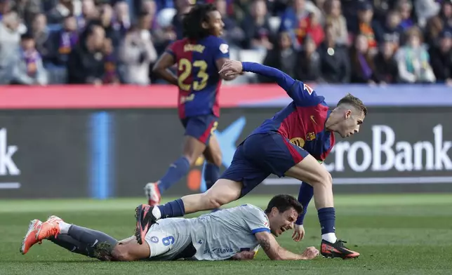 Alaves' Ander Guevara, falls by Barcelona's Fermin Lopez, right, during a Spanish La Liga soccer match between Barcelona and Alaves at the Lluis Companys Olympic Stadium in Barcelona, Spain, Sunday Feb. 2, 2025. (AP Photo/Joan Monfort)