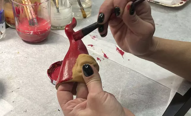 Marianna Mattei puts a final touch on Neapolitan horns in a shop in Naples, southern Italy, Wednesday, Feb. 12, 2025. (AP Photo/Giada Zampano)