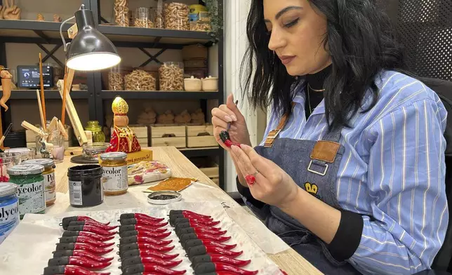 Serena D'Alessandro puts a final touch on Neapolitan horns in the family's shop in Naples, southern Italy, Wednesday, Feb. 12, 2025. (AP Photo/Trisha Thomas)