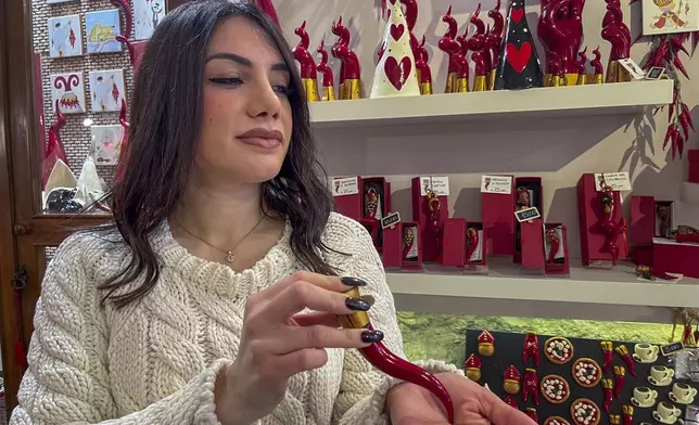 Delia D'Alessandro explains the origins and use of the Neapolitan horn in the family's shop in Naples, southern Italy, Wednesday, Feb. 12, 2025. (AP Photo/Giada Zampano)