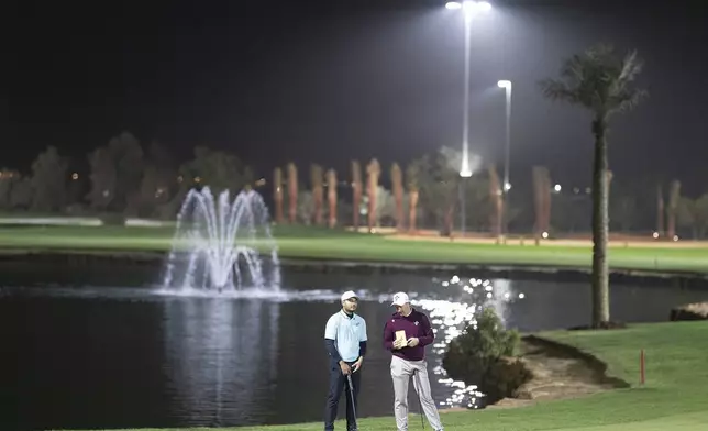 Sebastián Muñoz of Torque GC and Lucas Herbert of Ripper GC talk on the 13th green during the final round of the LIV Golf tournament at Riyadh Golf Club, Saturday, Feb. 8, 2025 in Riyadh, Saudi Arabia. (Photo by Charles Laberge/LIV Golf via AP)