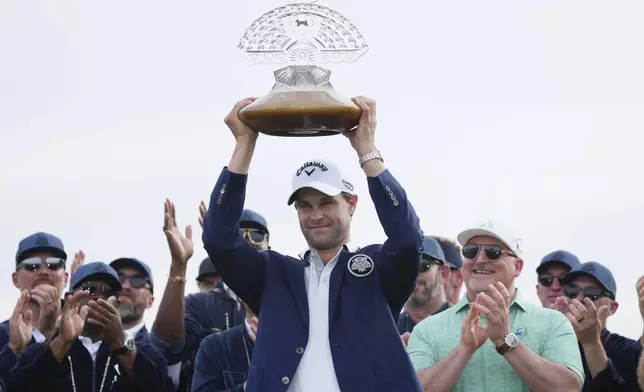 Thomas Detry, center, of Belgium, smiles as celebrates after his win at the Phoenix Open golf tournament at TPC Scottsdale while holding the winner's trophy and posing for photographers Sunday, Feb. 9, 2025, in Scottsdale, Ariz. (AP Photo/Ross D. Franklin)