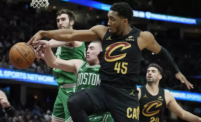 Boston Celtics center Luke Kornet, left, guard Payton Pritchard, center, and Cleveland Cavaliers guard Donovan Mitchell (45) reach for a rebound in the second half of an NBA basketball game, Tuesday, Feb. 4, 2025, in Cleveland. (AP Photo/Sue Ogrocki)