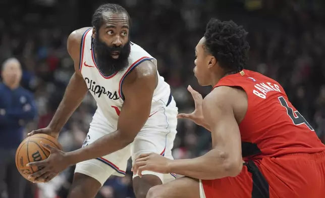 Los Angeles Clippers guard James Harden, left, controls the ball as Toronto Raptors forward Scottie Barnes (4) defends during first-half NBA basketball game action in Toronto, Sunday, Feb. 2, 2025. (Frank Gunn/The Canadian Press via AP)