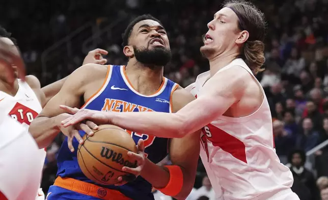 New York Knicks' Karl-Anthony Towns, left, drives at Toronto Raptors' Kelly Olynyk, right, during the second half of an NBA basketball game in Toronto, Tuesday, Feb. 4, 2025. (Nathan Denette/The Canadian Press via AP)