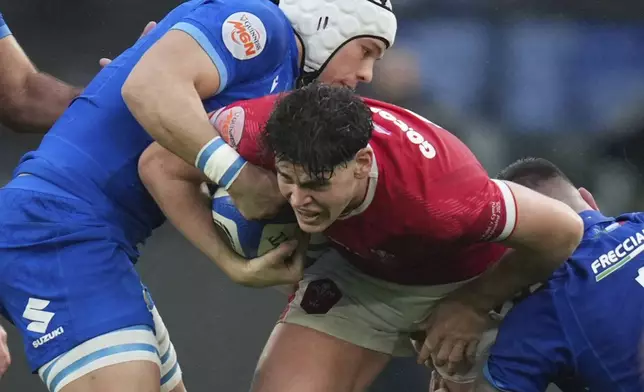 Wale's Eddie James, center, is tackled by defenders during the Six Nations rugby union match between Italy and Wales at the Olympic Stadium in Roma, Italy, Saturday, Feb. 8, 2025. (AP Photo/Alessandra Tarantino)