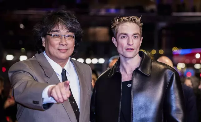Actor Robert Pattinson, right, and Bong Joon-ho, left, pose for the photographers as they arrive for the screening of the film 'Mickey 17' at the International Film Festival, Berlinale, in Berlin, Saturday, Feb. 15, 2025. (Christoph Soeder/dpa via AP)