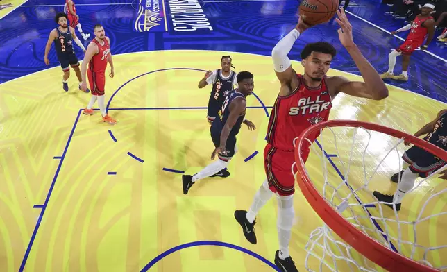 San Antonio Spurs center Victor Wembanyama, center, dunks in front of Memphis Grizzlies forward Jaren Jackson Jr. (13) during the NBA basketball All-Star game Sunday, Feb. 16, 2025, in San Francisco. (Ezra Shaw/Pool Photo via AP)