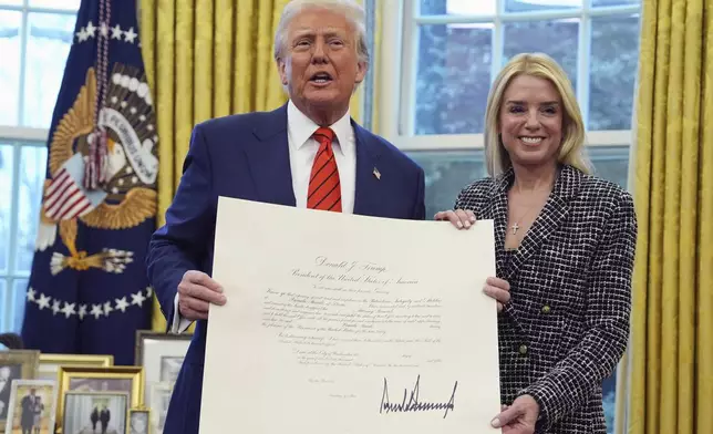 President Donald Trump presents Attorney General Pam Bondi with a document, after she was sworn in by Supreme Court Associate Justice Clarence Thomas, in the Oval Office of the White House, Wednesday, Feb. 5, 2025, in Washington. (AP Photo/Evan Vucci)