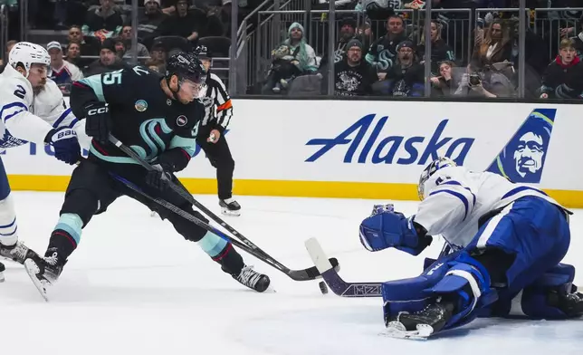 Toronto Maple Leafs goaltender Anthony Stolarz, right, makes a stop against Seattle Kraken left wing Andre Burakovsky, center, as Maple Leafs defenseman Simon Benoit, left, defends during the second period of an NHL hockey game Thursday, Feb. 6, 2025, in Seattle. (AP Photo/Lindsey Wasson)