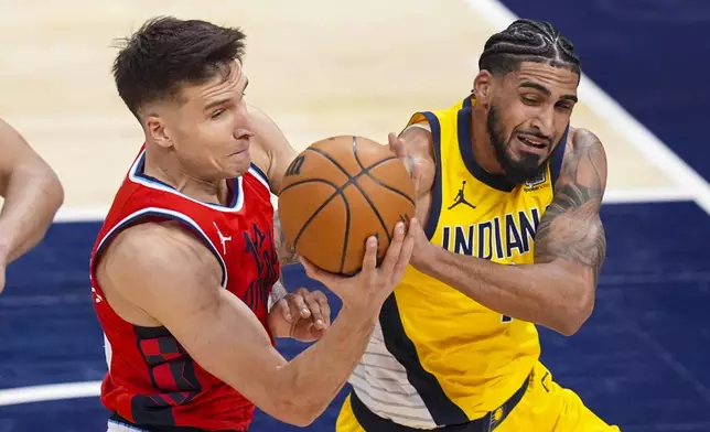 Indiana Pacers forward Obi Toppin (1) and LA Clippers guard Bogdan Bogdanovic (10) get tied up as they go for rebound during the first half of an NBA basketball game in Indianapolis, Sunday, Feb. 23, 2025. (AP Photo/Michael Conroy)