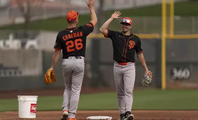 San Francisco Giants shortstop Willy Adames, right, and San Francisco Giants third base Matt Chapman (26), high-five during spring training baseball practice at the team's training facility, Monday, Feb. 17, 2025, in Scottsdale, Ariz. (AP Photo/Carolyn Kaster)