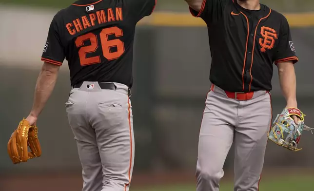 San Francisco Giants shortstop Willy Adames, right, and San Francisco Giants third base Matt Chapman (26), high-five during spring training baseball practice at the team's training facility, Monday, Feb. 17, 2025, in Scottsdale, Ariz. (AP Photo/Carolyn Kaster)