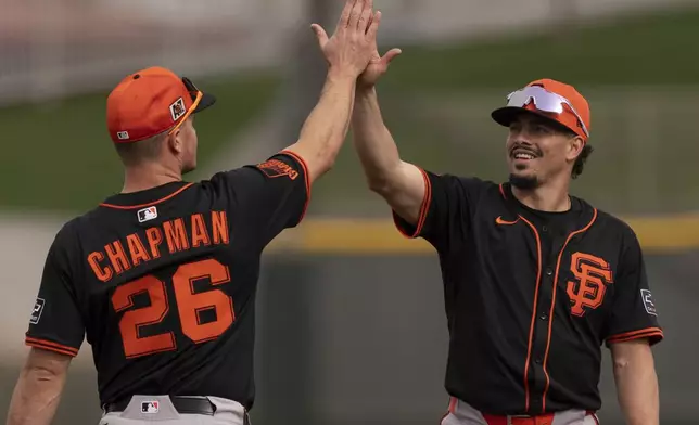 San Francisco Giants shortstop Willy Adames, right, and San Francisco Giants third base Matt Chapman (26), high-five during spring training baseball practice at the team's training facility, Monday, Feb. 17, 2025, in Scottsdale, Ariz. (AP Photo/Carolyn Kaster)