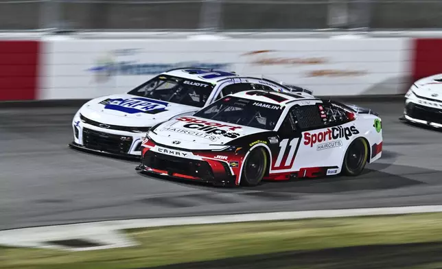 Denny Hamlin (11) and Chase Elliott (9) compete into Turn 1 during a NASCAR Cup Series auto race at Bowman Gray Stadium, Sunday, Feb. 2, 2025, in Winston-Salem, N.C. (AP Photo/Matt Kelley)
